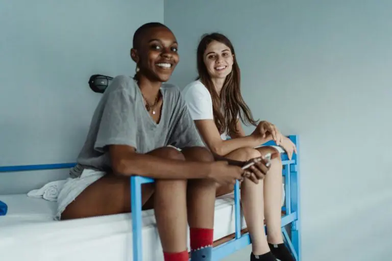 Two Women Sitting on a Bunk Bed and Smiling